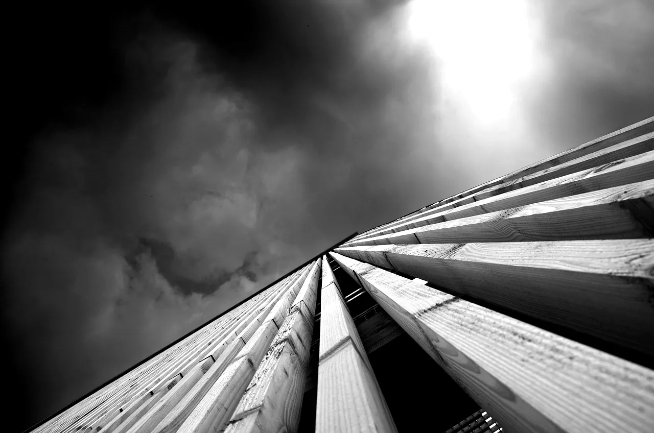 Façade d'un bâtiment à ossature bois vue en contre-plongée sous un ciel d'orage
